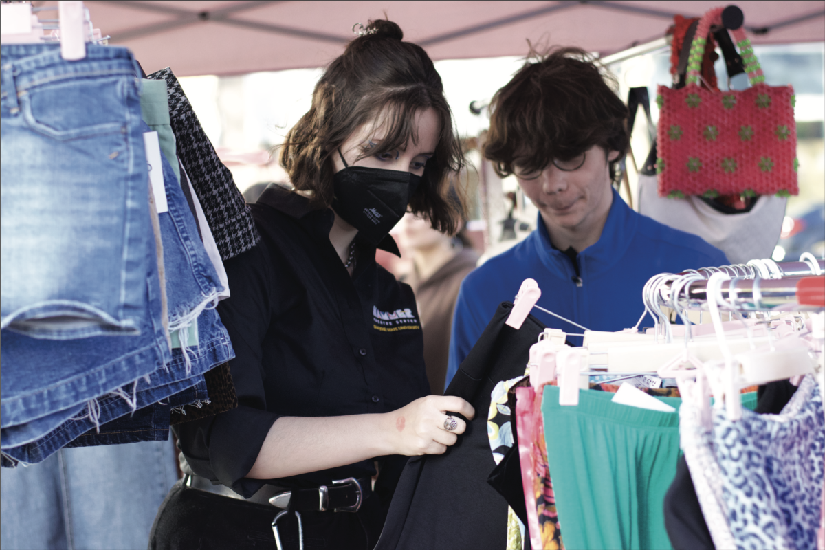 Jordan Michelena (left) and their partner, Lucas Robin (right), both third-year theatre art students, look through a circular clothes rack filled with a variety of colorful pieces of clothing while visiting the vintage pop-up market, So-So Market, in San 